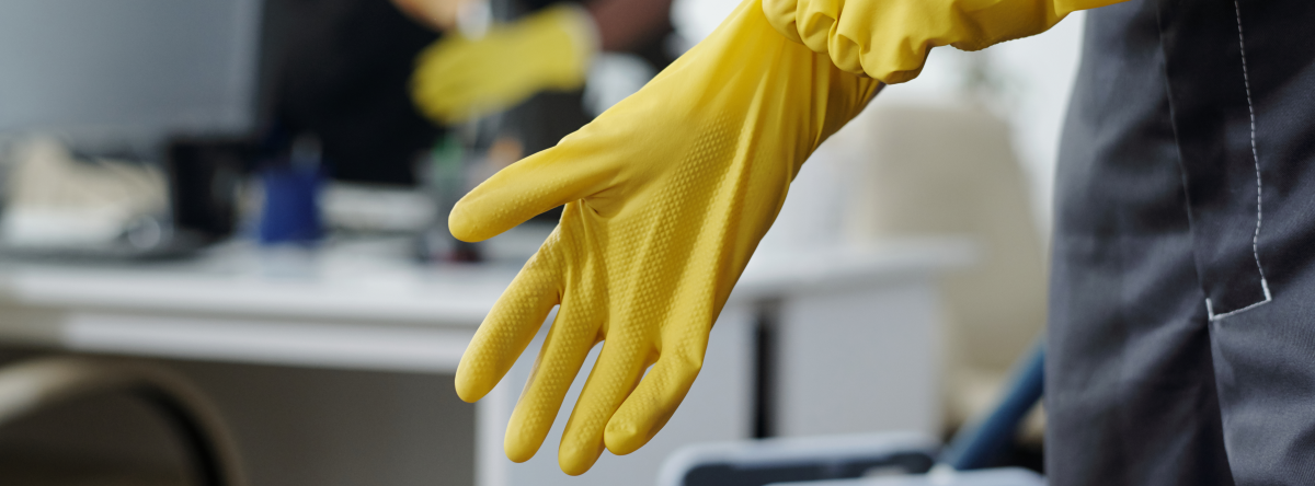 Une personne enfile des gants pour nettoyer le bureau