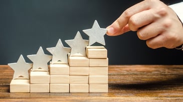 Blocs et étoiles en bois empilés pour démontrer la corrélation entre l’expérience client et la croissance dans une entreprise